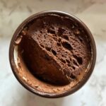 Overhead view of rich, airy chocolate mousse in a small brown serving cup.