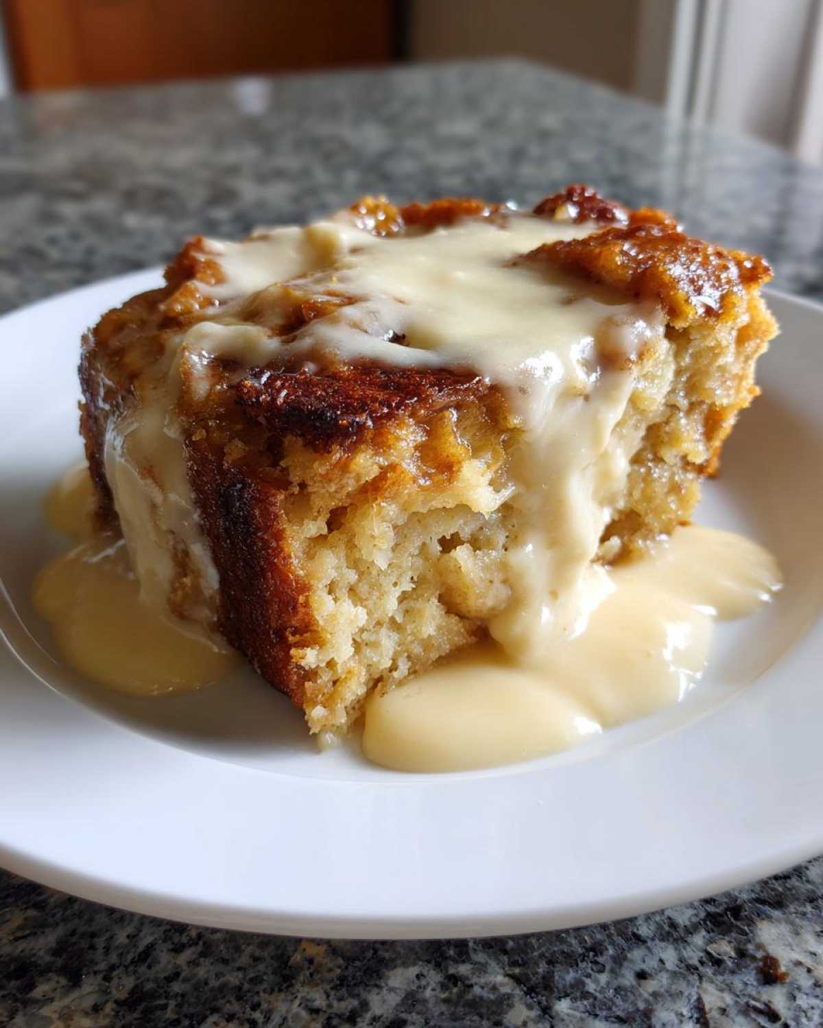A moist, golden slice of bread pudding topped with rich vanilla sauce or custard.