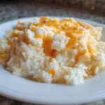 A generous serving of creamy, white rice topped with melted orange cheddar cheese, showcasing the amazing cheesy rice recipe.
