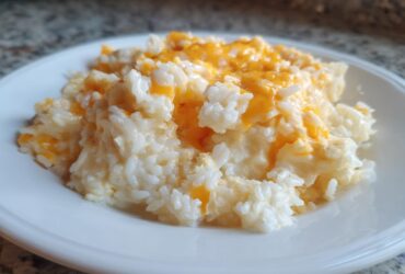 A generous serving of creamy, white rice topped with melted orange cheddar cheese, showcasing the amazing cheesy rice recipe.