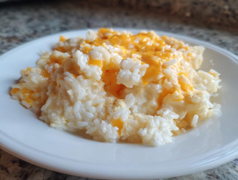 A generous serving of creamy, white rice topped with melted orange cheddar cheese, showcasing the amazing cheesy rice recipe.