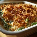 Close-up of a baked green bean casserole topped with a thick layer of golden, crispy fried onions.