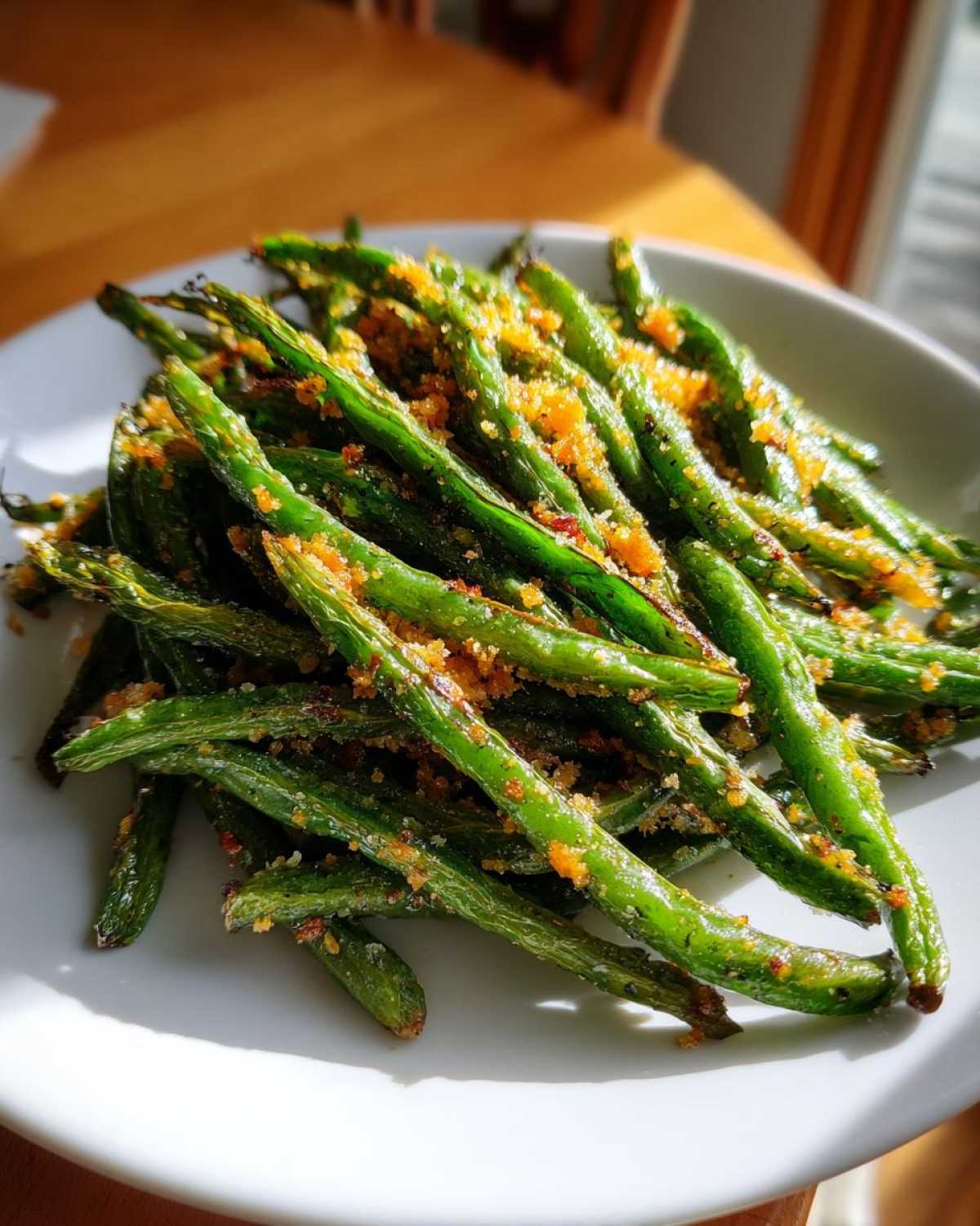 Close-up of bright green beans tossed with crispy breadcrumbs, ready to serve.
