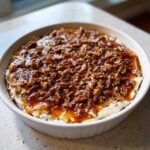 A creamy, white base topped generously with sticky caramel sauce and chopped pecans for pecan pie dip.