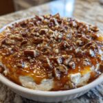 A close-up of the amazing pecan pie dip, featuring a creamy base topped with gooey caramel sauce and chopped pecans.