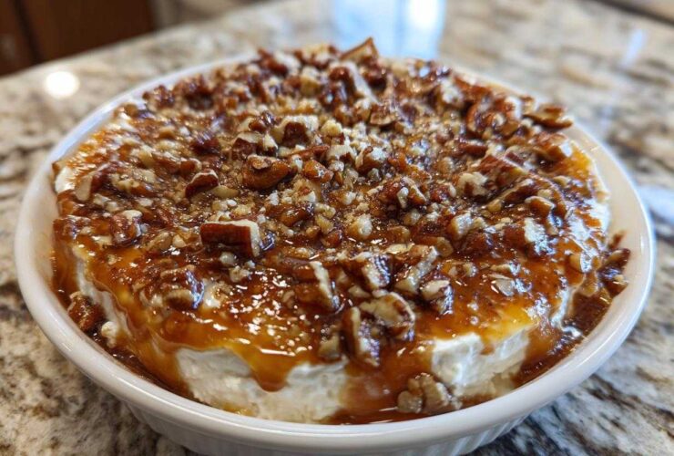 A close-up of the amazing pecan pie dip, featuring a creamy base topped with gooey caramel sauce and chopped pecans.