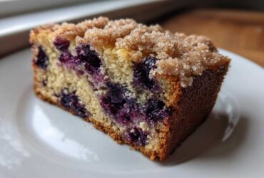 Close-up of a moist slice of blueberry banana bread topped with brown sugar streusel.
