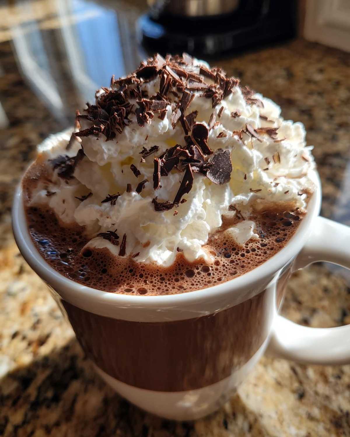 Close-up of a mug filled with rich boozy hot chocolate, topped with whipped cream and chocolate shavings.