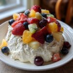 A mound of creamy cheesecake filling topped generously with mixed fresh fruit, creating an incredible cheesecake fruit salad.