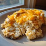 A close-up serving of creamy cheesy chicken and rice topped with melted cheddar cheese.