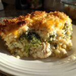 A generous slice of creamy chicken broccoli rice casserole topped with melted cheddar and a golden, crispy crust.