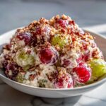 Close-up of creamy chicken salad chick grape salad mixed with red and green grapes and topped with chopped pecans.