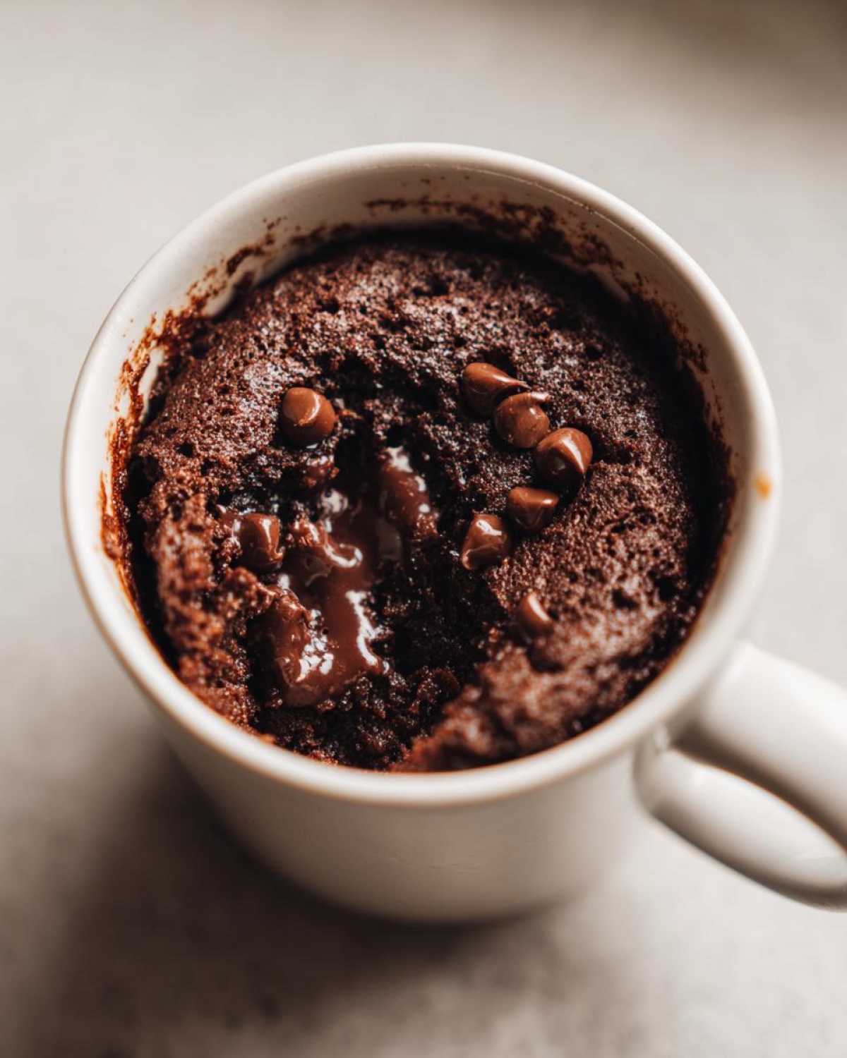 Close-up of a rich chocolate mug cake with melted chocolate chips inside, ready to eat.