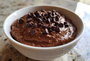 Close-up of thick, rich chocolate overnight oats topped generously with dark chocolate chips in a white bowl.