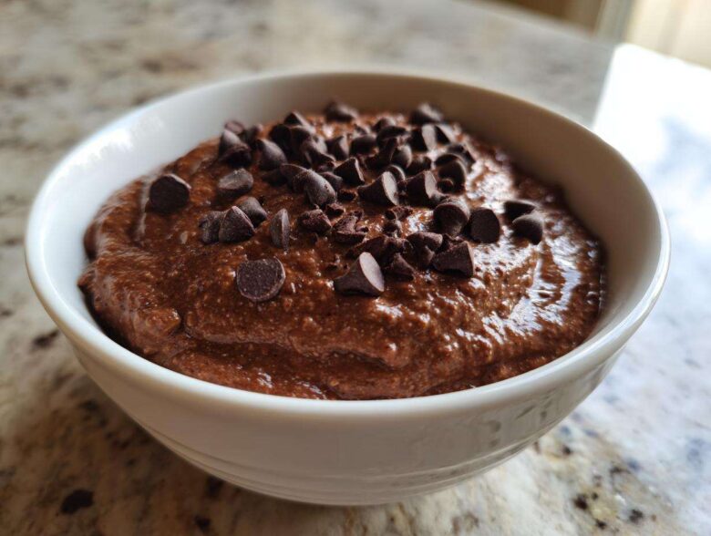 Close-up of thick, rich chocolate overnight oats topped generously with dark chocolate chips in a white bowl.