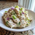 Close-up of creamy cottage cheese chicken salad mixed with celery and red onion in a white bowl.