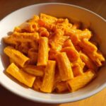 A close-up of creamy butternut squash pasta made with rigatoni, served in a white bowl.