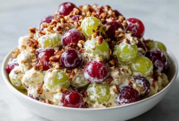 Close-up of a creamy chicken salad chick grape salad mixture with red and green grapes and chopped pecans.