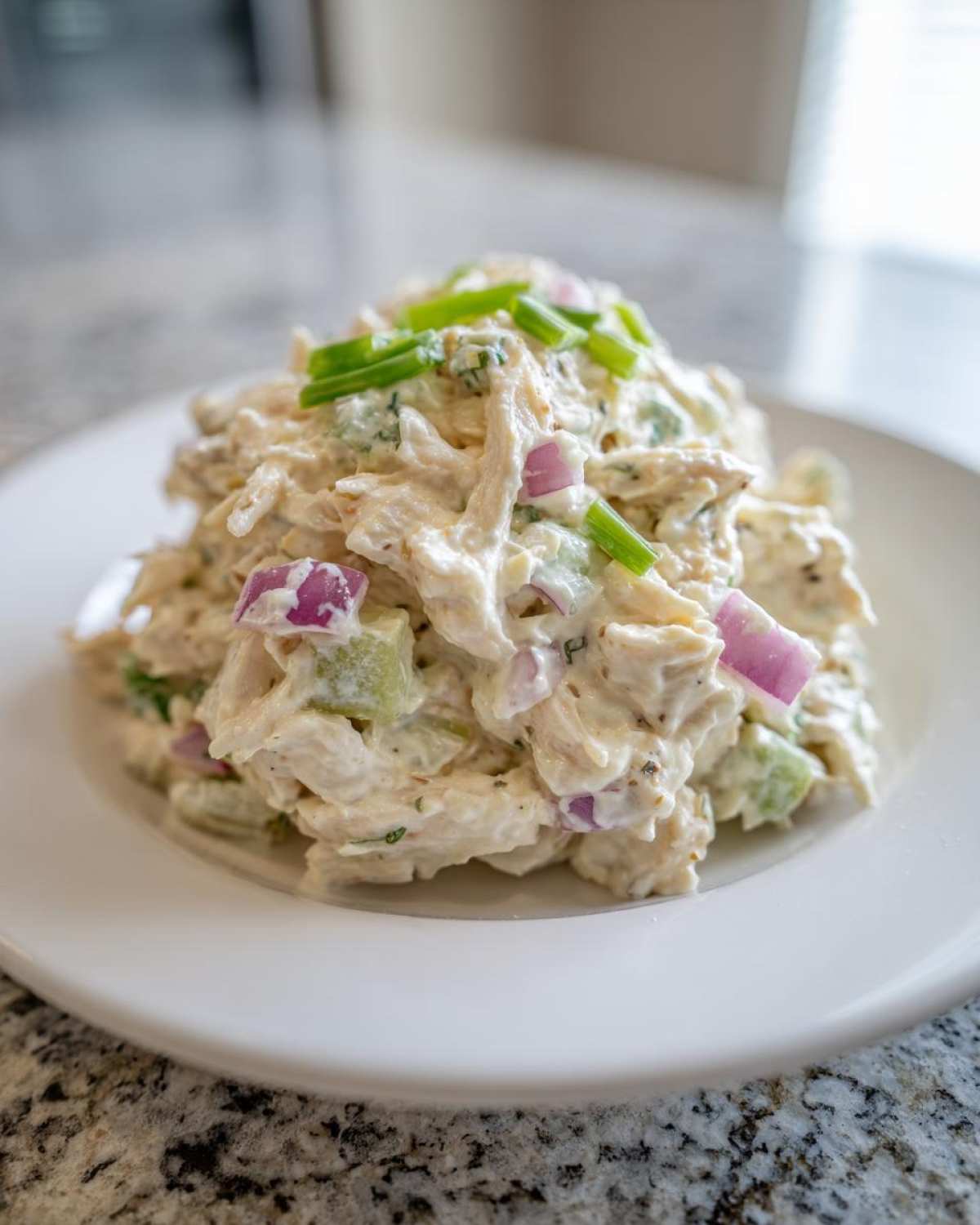 A scoop of creamy cottage cheese chicken salad mixed with red onion and celery, topped with fresh chives.