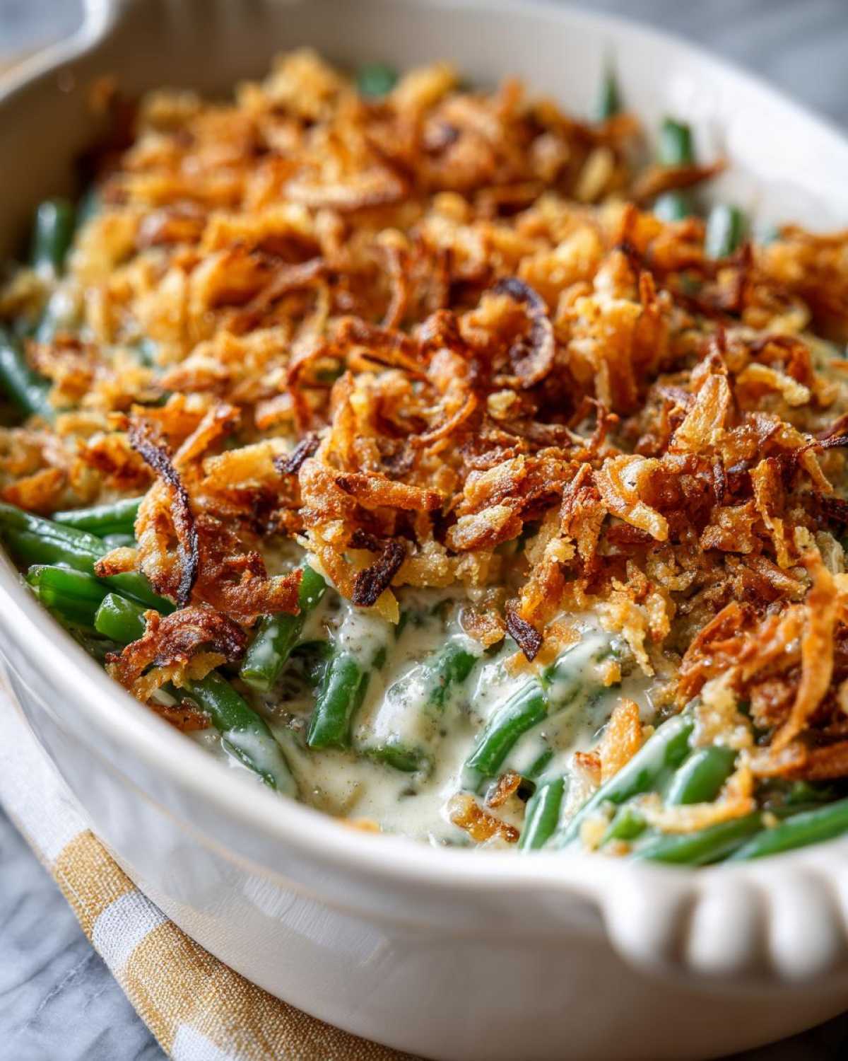 A close-up view of a creamy green bean casserole topped generously with crispy fried onions.