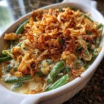 Close-up of a creamy green bean casserole topped generously with crispy fried onions.