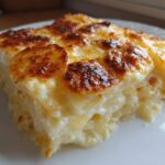 A close-up of a rich, creamy slice of potatoes au gratin with a golden-brown, bubbly cheese crust.
