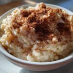 Close-up of a bowl of creamy rice pudding generously sprinkled with ground cinnamon.