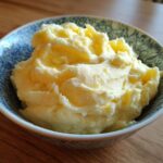 A close-up of creamy, fluffy roasted garlic mashed potatoes served in a decorative blue and white bowl.