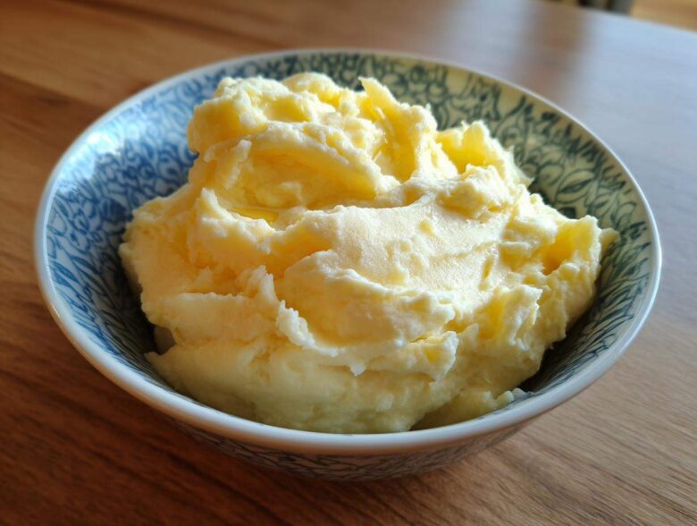 A close-up of creamy, fluffy roasted garlic mashed potatoes served in a decorative blue and white bowl.