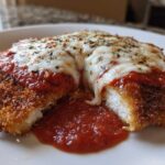 Close-up of Easy Chicken Parmesan cut open, showing melted mozzarella, marinara sauce, and crispy breading.
