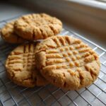 Close-up of freshly baked Easy Peanut Butter Cookies cooling on a wire rack with crosshatch fork marks.