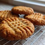 Close-up of several Easy Peanut Butter Cookies with classic crosshatch fork marks cooling on a wire rack.