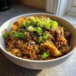 Close-up of a savory Egg Roll in a Bowl topped with fresh green onions and sesame seeds.
