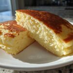 Close-up of two halves of thick, fluffy almond flour pancakes showing the light, airy interior and golden-brown tops.