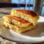 Close-up of three stacked almond flour pancakes cut in half, showing their fluffy texture and golden-brown edges.