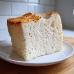 Close-up of a perfectly baked slice of angel food cake showing its airy, white interior and light golden crust.