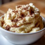 A close-up of creamy, whipped cinnamon butter generously sprinkled with ground cinnamon in a white bowl.