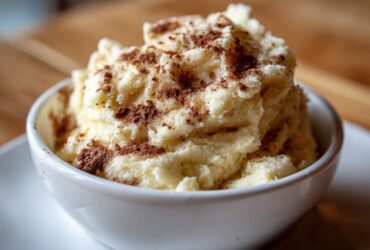 A close-up of creamy, whipped cinnamon butter generously sprinkled with ground cinnamon in a white bowl.