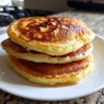 Close-up of a stack of three fluffy greek yogurt pancakes with golden-brown tops.