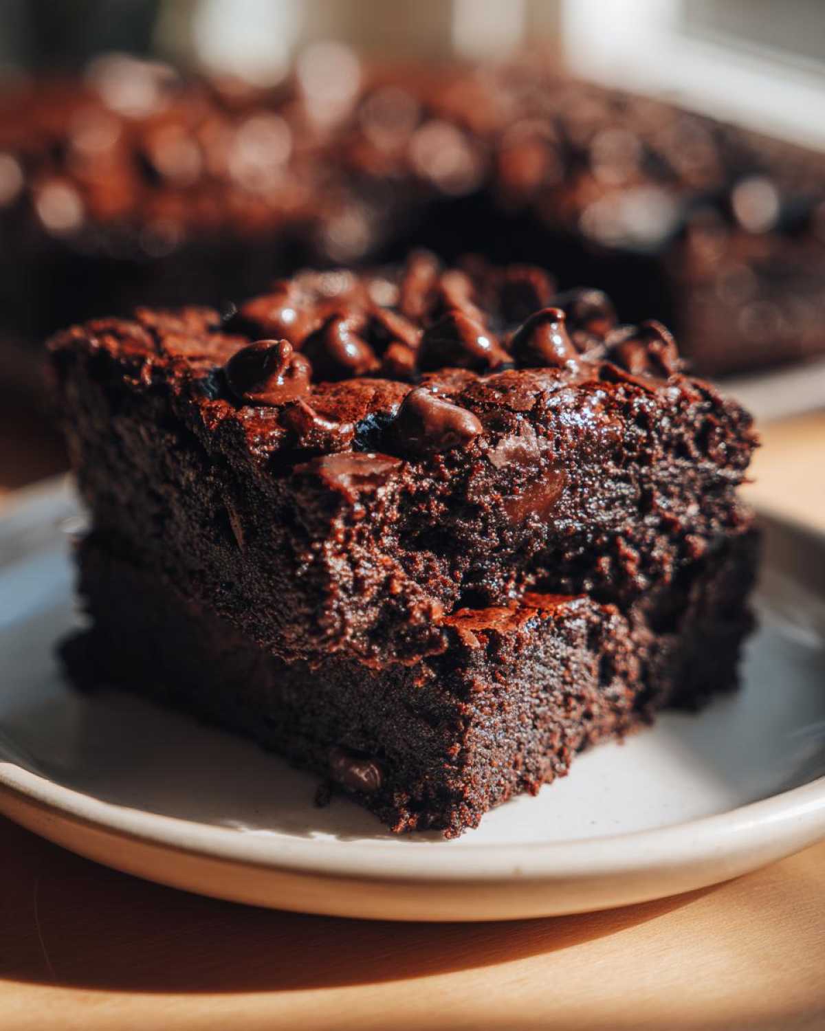 Two stacked, fudgy black bean brownies topped generously with melted chocolate chips.