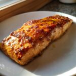 A perfectly cooked, glazed salmon fillet seasoned with mustard and spices, ready to eat.