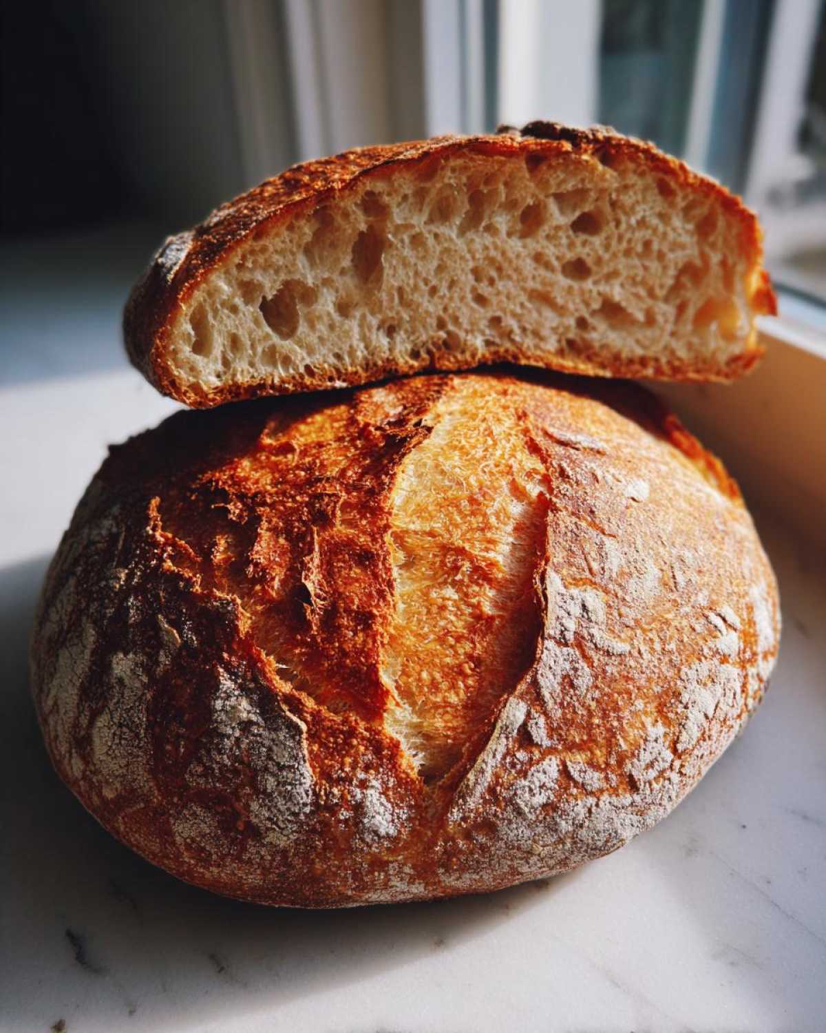 A rustic loaf of Italian bread, cut in half to show the airy interior crumb and crisp, golden crust.
