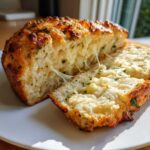 Close-up of Italian herb and cheese bread sliced open showing melted, stringy cheese pull.