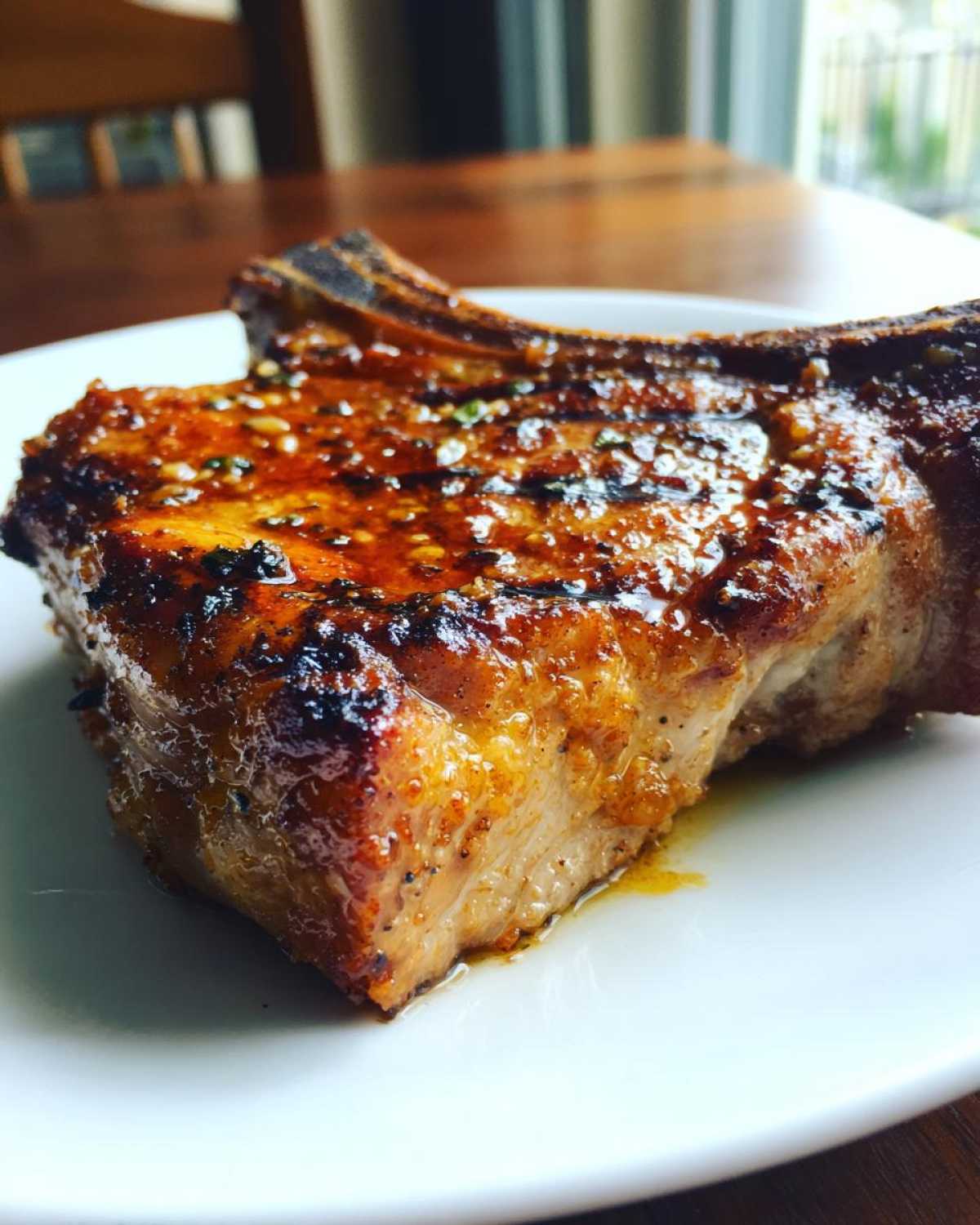 Close-up of a thick, juicy, bone-in pork chop showing a caramelized glaze, a result of the best marinade for pork chops.