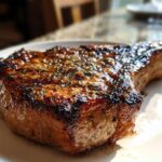 Close-up of a thick, perfectly seared pork chop showing a rich, caramelized glaze from the marinade for pork chops.