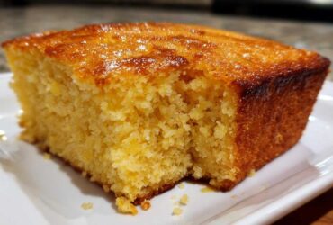 Close-up of a golden, moist slice of buttermilk cornbread with a shiny, slightly caramelized top.