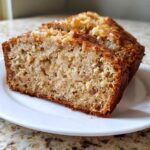 Close-up of a moist slice of Hawaiian banana bread showing the rich texture and caramelized top.
