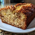 A close-up of a moist slice of Hawaiian banana bread with a caramelized, dark brown crust.