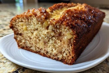 A close-up of a moist slice of Hawaiian banana bread with a caramelized, dark brown crust.