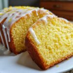 Close-up of a sliced lemon pound cake topped with white glaze and lemon zest.